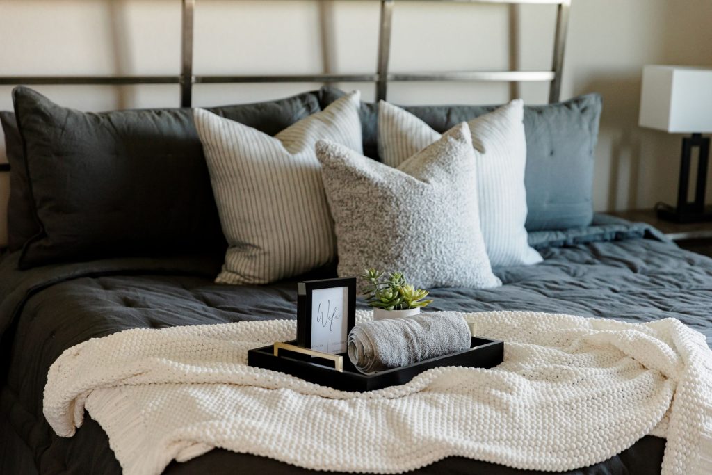 Hotel-style guest bedroom with layered bedding, accent pillows, and a welcoming tray on the bed