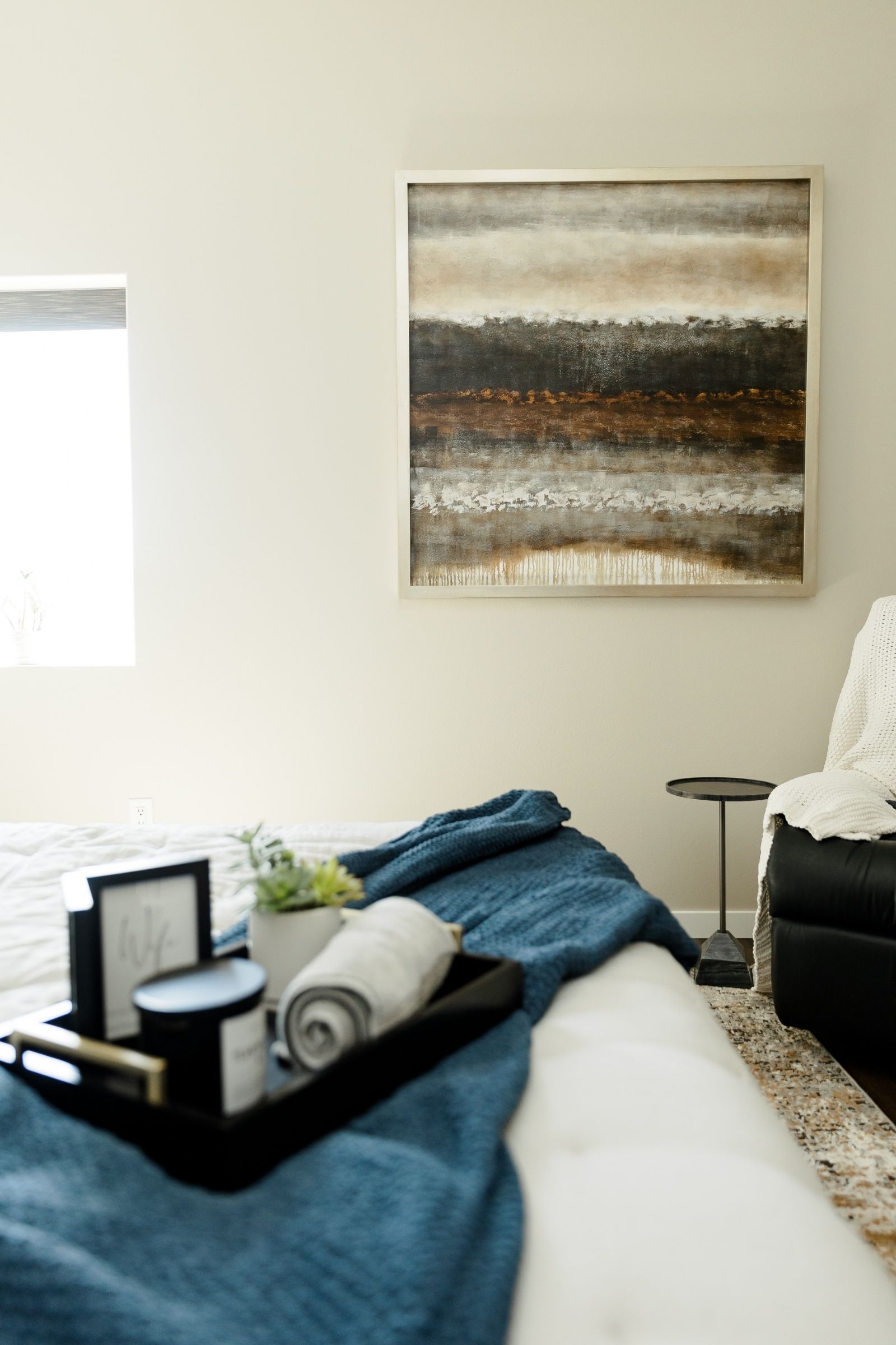Guest bedroom styled with a welcome tray, folded blanket, and artwork for a hotel-inspired feel