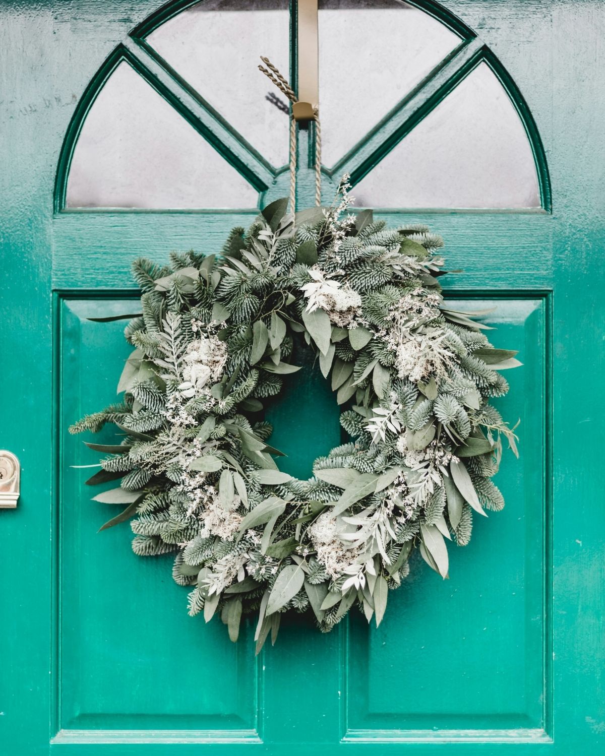 faux wreath that looks real hanging on a green front door