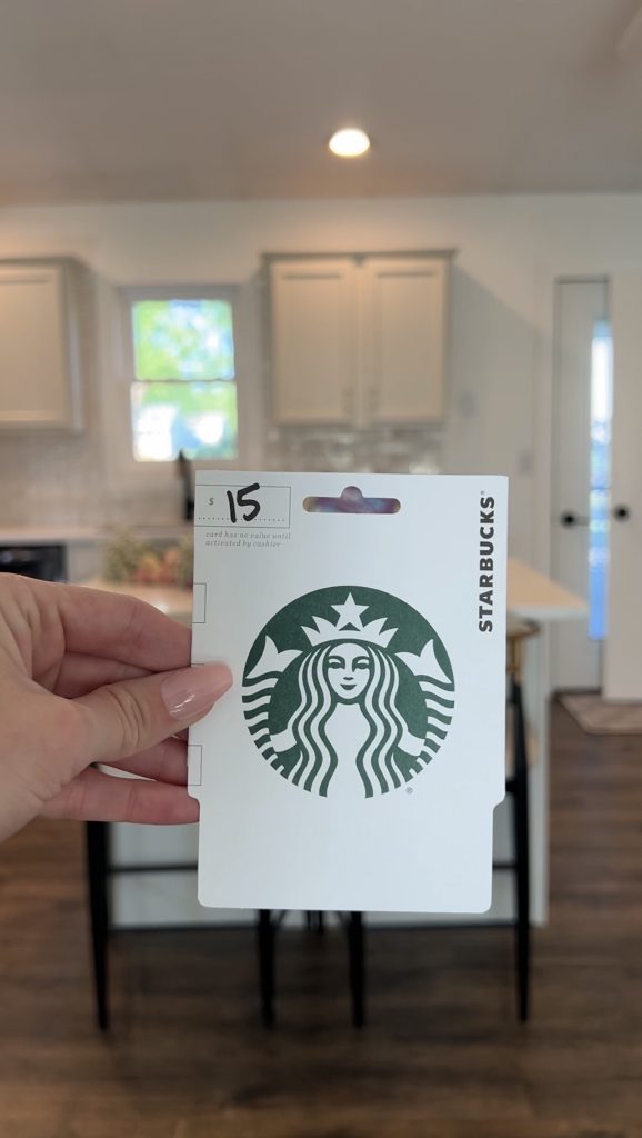 Hand holding a Starbucks gift card included in a feminine bloom basket gift arrangement.